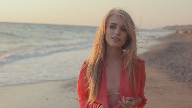 Young blond girl with long hair in red blouse on the beach