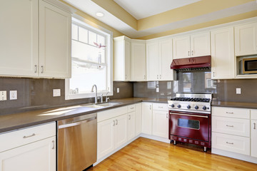 White kitchen with burgundy stove and grey counter tops