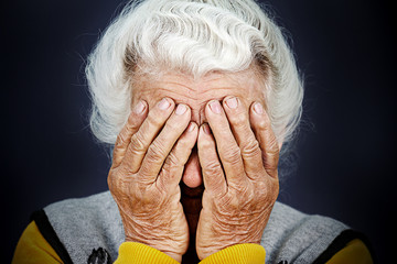 Closeup portrait depressed old woman covering her face with hand