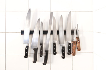 Set of knives on magnetic holder on white tiles