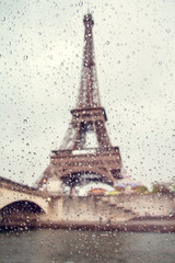 View on the Eiffel Tower through the window with rain drops.