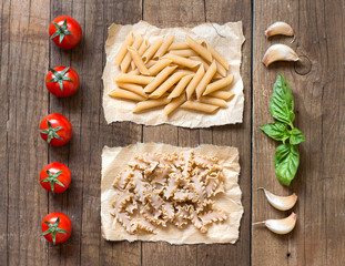 Pasta, tomatoes, garlic and basil on the wooden table