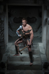 Gladiator in armour standing on steps of ancient temple with swo