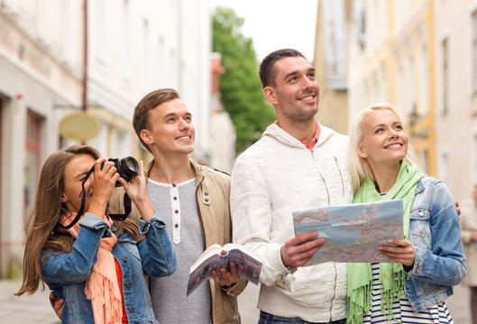 group of friends with city guide, map and camera