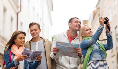 group of friends with city guide, map and camera