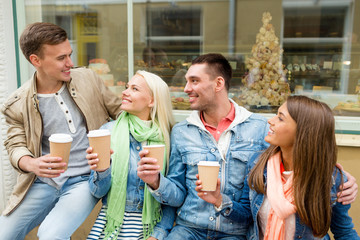 group of smiling friends with take away coffee