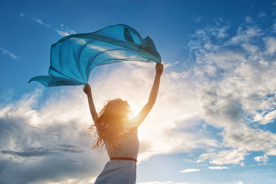 Beautiful young woman holding blue scarf on the wind