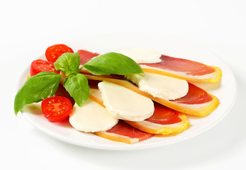 Sliced prosciutto and mozzarella with basil and tomatoes