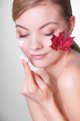 Fototapeta na wymiar Skin care. Face of young woman girl with red maple leaf.