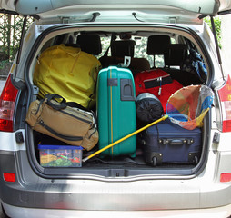 trunk of the car with fishing net and luggage bags ready for the