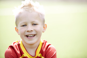 Seven year old boy sitting on a football field