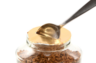 Teaspoon breaking the foil seal on a jar of coffee