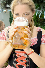 Frau im Dirndl trinkt Bier aus Maßkrug