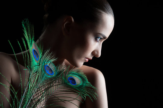 Beautiful brunette young woman with peacock style make-up and pe