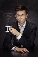 Smart young businessman holding the cup of vaporous coffee