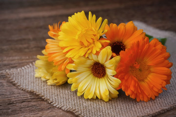 Bouquet of calendulas on canvas on old wooden background