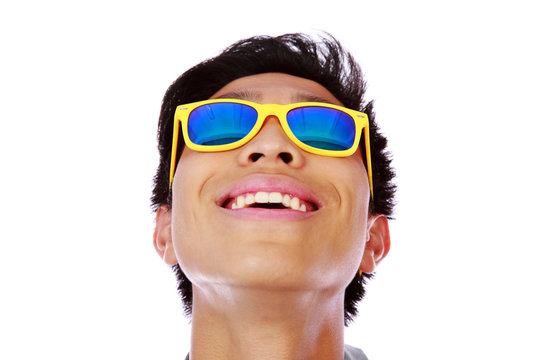 Happy asian man in yellow sunglasses looking up
