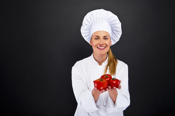 Portrait of young woman chef with tomatos
