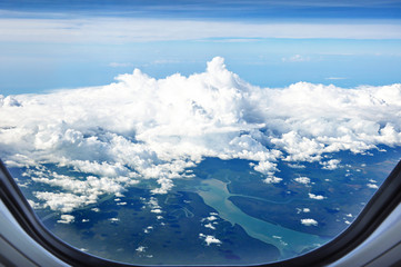 Aerial view of land and rivers with clouds from airplane window