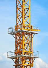 Fototapeta na wymiar Yellow construction tower crane against blue sky