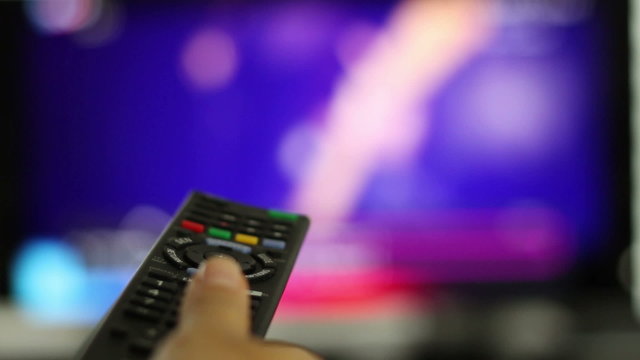 Watching TV and using remote controller, close up