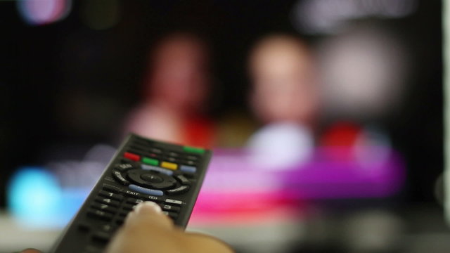 Watching TV and using remote controller, close up