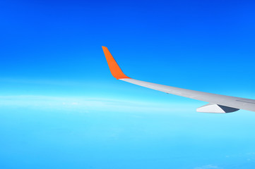Fototapeta na wymiar Airplane wing on clear blue sky background