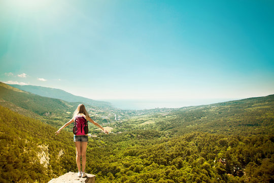 Young woman with backpack standing on cliff edge