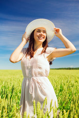 smiling young woman in straw hat on cereal field