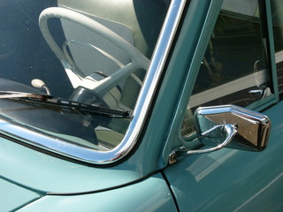 Blick in den Innenraum einer Limousine der Fünfziger Jahre mit weißem Lenkrad im Sonnenschein...