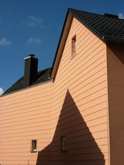 Schatten eines spitzten Giebel auf einer Fassade in Apriciot mit Spitzgiebel im Sommer bei blauem...