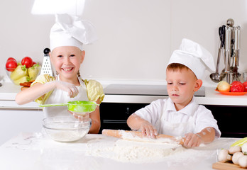 Two happy young children learning to bake