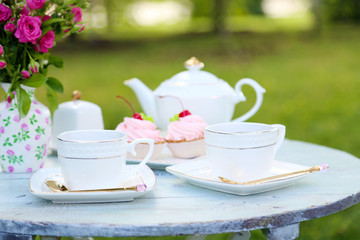 Coffee table with teacups and tasty cakes in garden