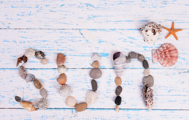 Word sun made from sea shells and stones on wooden background