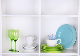 Kitchen utensils and tableware on beautiful white shelves