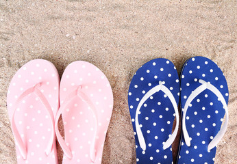 Fototapeta premium Color flip-flops on sand background