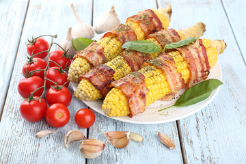 Grilled bacon wrapped corn on table, close-up
