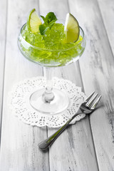 Green jelly with mint leaves in glass on wooden background
