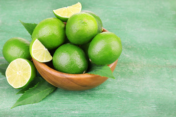 Fresh juicy limes in bowl  old wooden table