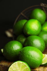 Fresh juicy limes on wooden table, on dark background