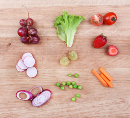Different slices of vegetables and berries on wooden table