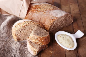 Fresh baked bread wrapped in paper and bowl with sauce,