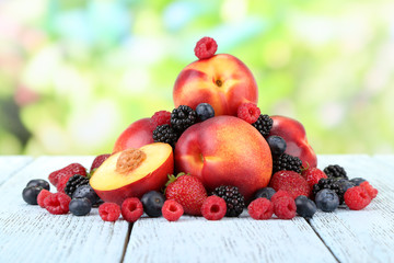 Peaches with berries on table on natural background