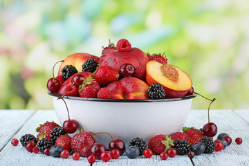 Peaches and berries in bowl on table on natural background
