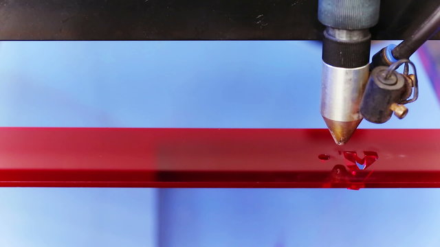 Laser cnc machine cutting technology word on red acryl plate