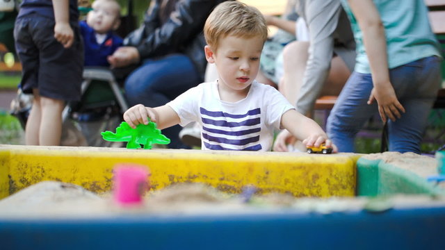 Child playing with toys in sand-pit