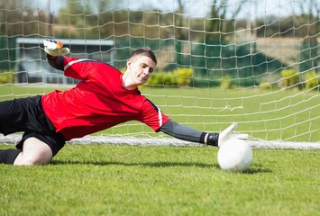 Goalkeeper in red saving a goal during a game