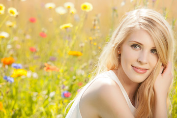 Hübsche blonde Frau vergnügt sich auf einer Blumenwiese