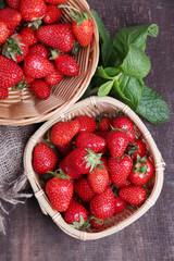 Ripe sweet strawberries in wicker basket and mint leaves