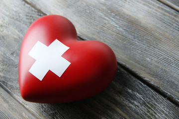 Red heart with cross sign on wooden background